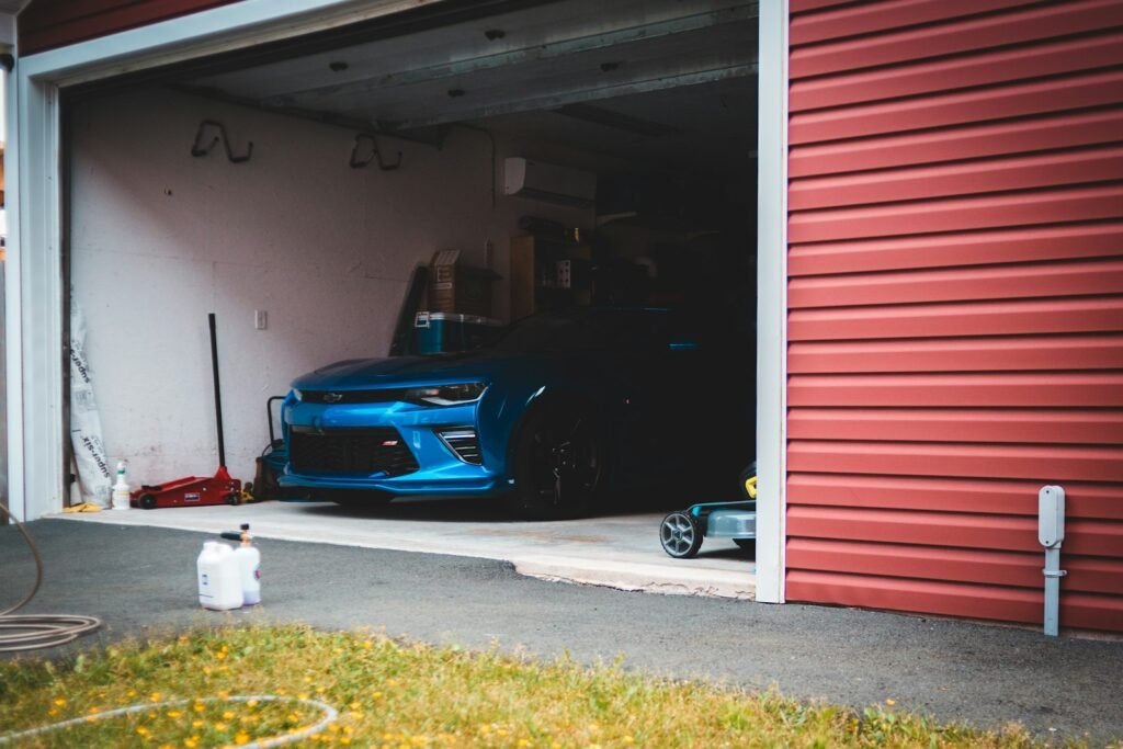 Blue car parked beside red garage door